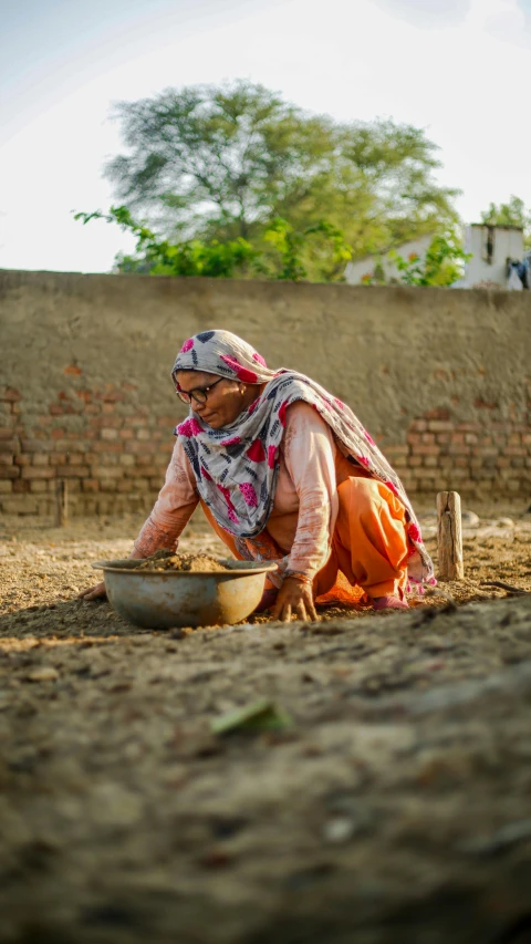 a woman is cooking food outside in the dirt