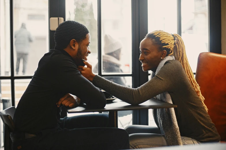 two people sitting at a table shaking hands