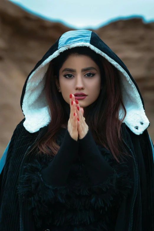 a woman is standing in front of a mountain praying