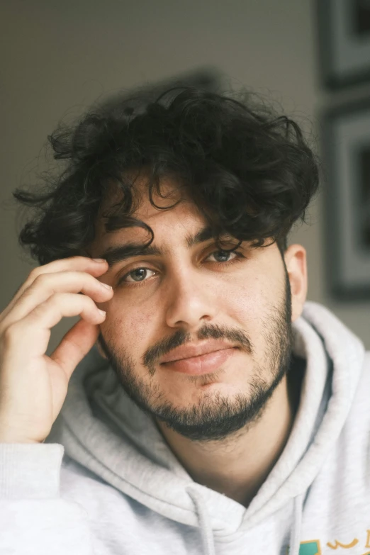 a man with curly hair wearing a gray sweatshirt