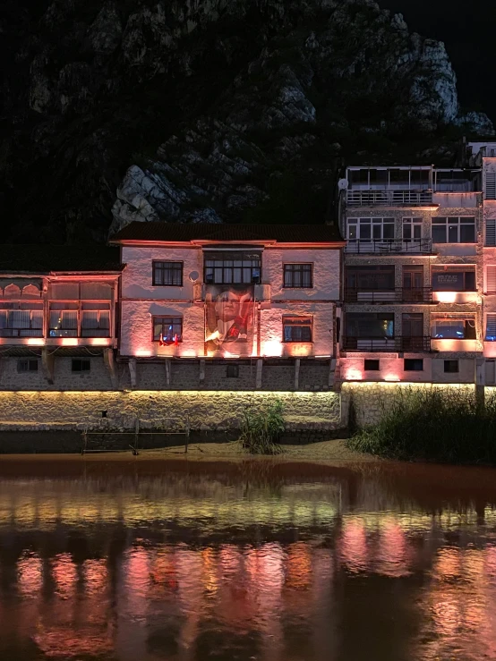 an illuminated building is next to a river at night