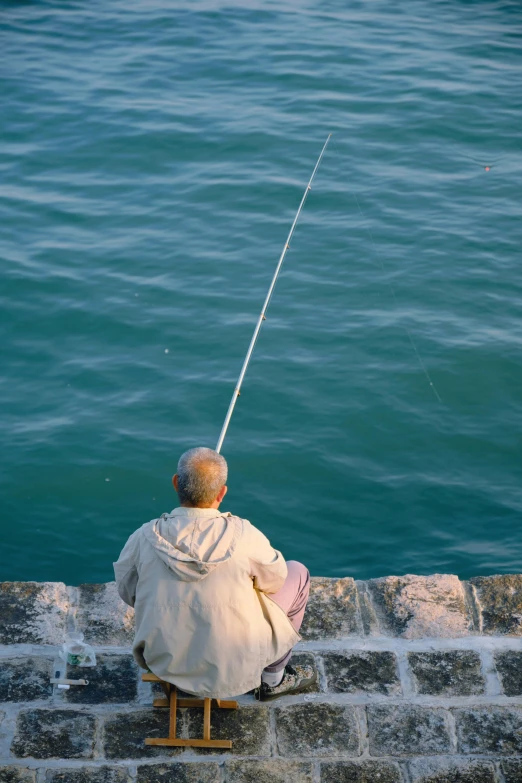 a young child sitting on a dock with a fishing rod