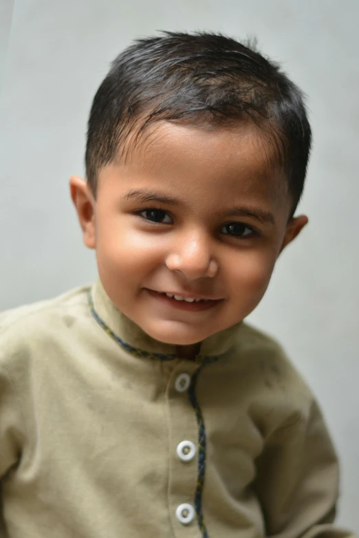 a little boy wearing a shirt and smiling