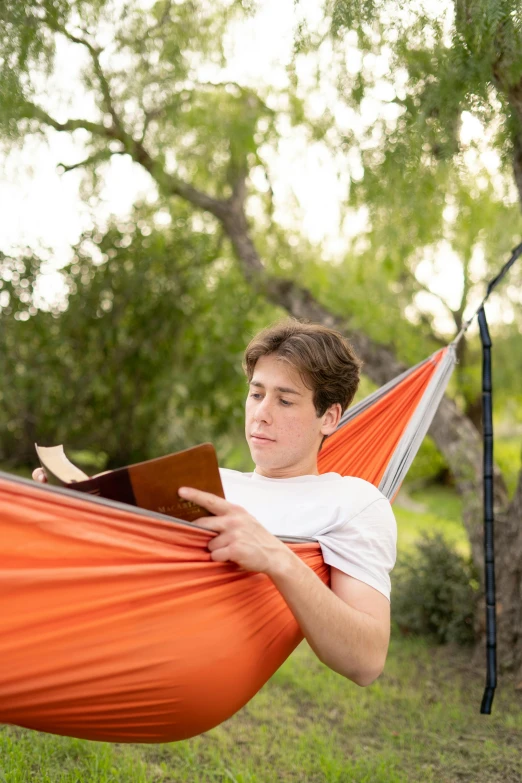 a person laying in a hammock reading a book