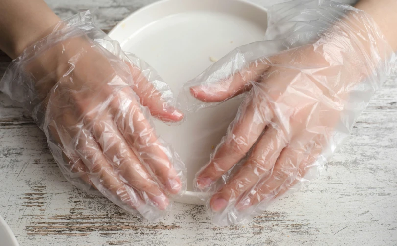 a person in clear gloves and gloves is over a white plate