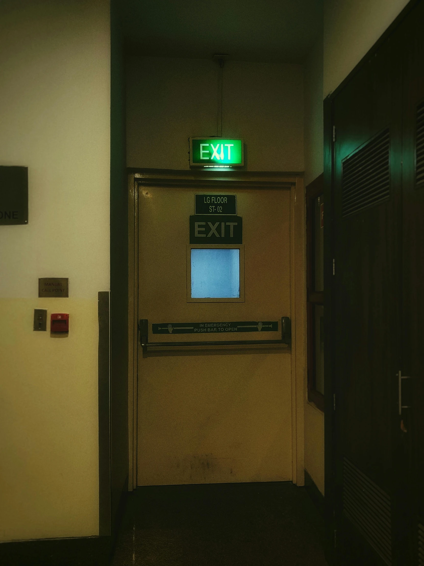 the exit sign is displayed in a very dark hallway