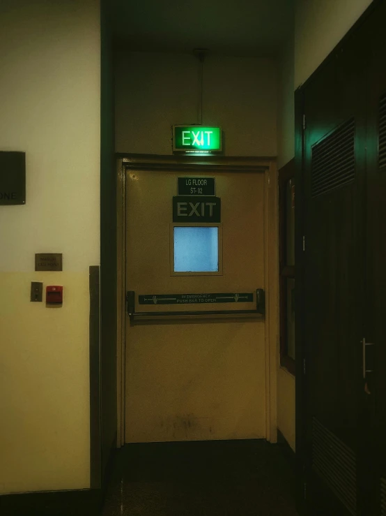 the exit sign is displayed in a very dark hallway