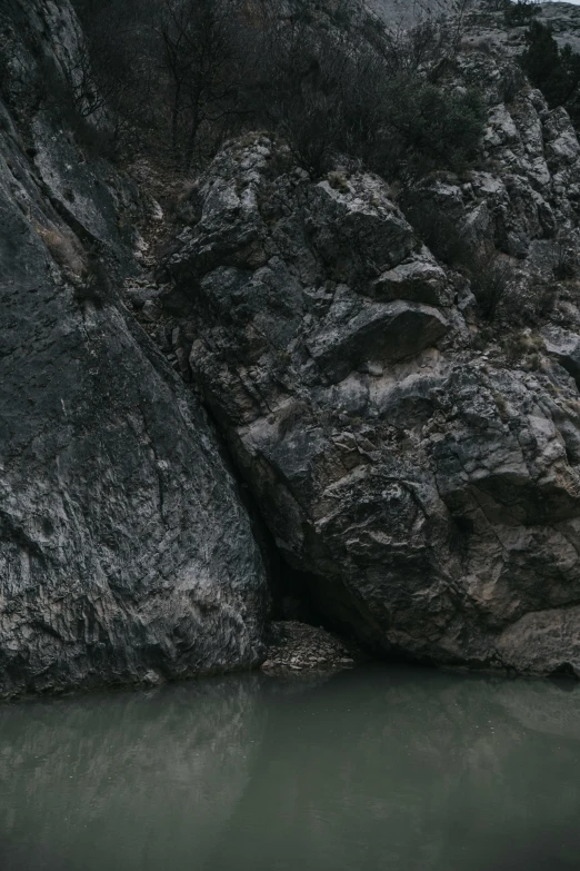 an image of a large rock side by side with the water below it