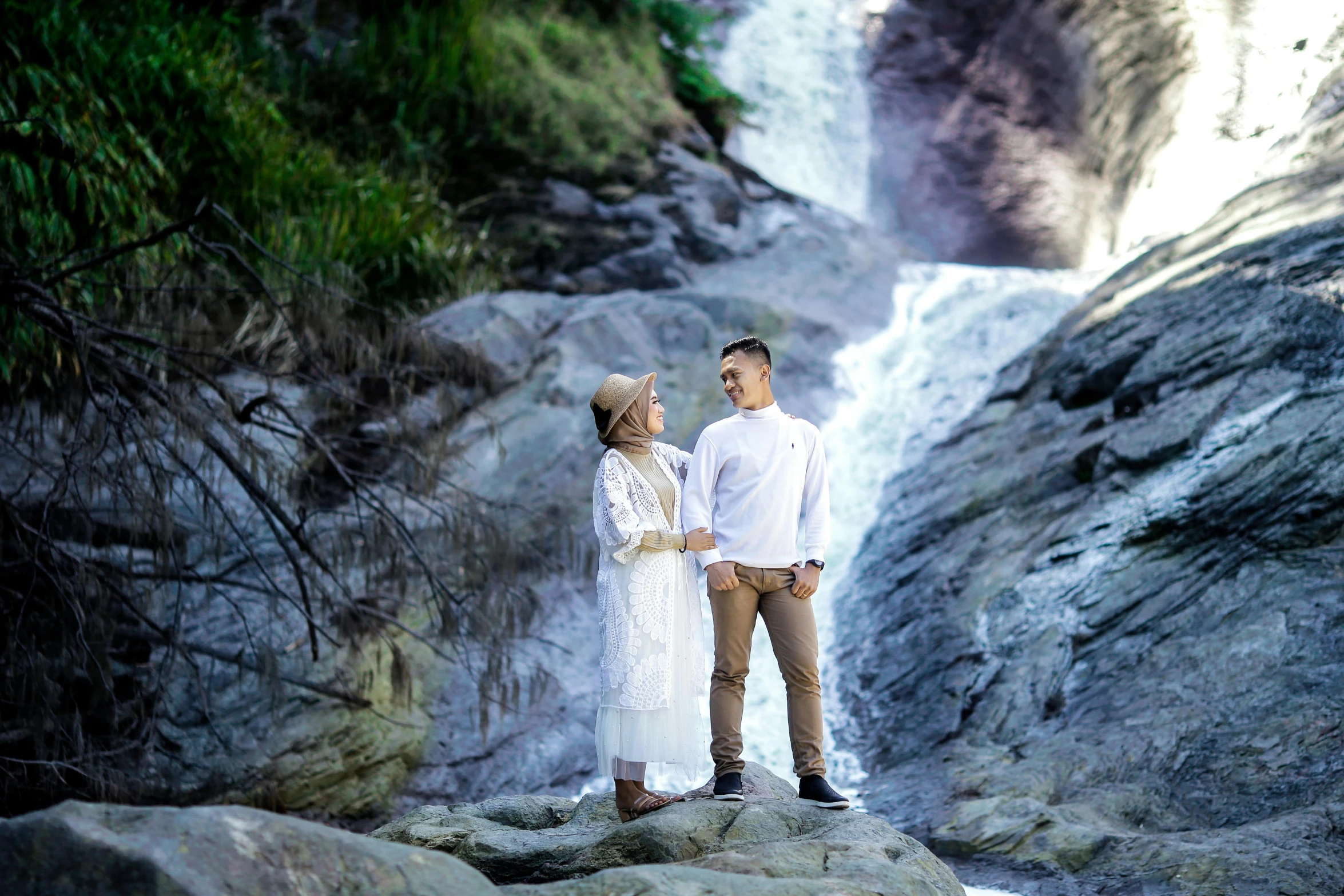 a young couple is looking at the waterfall