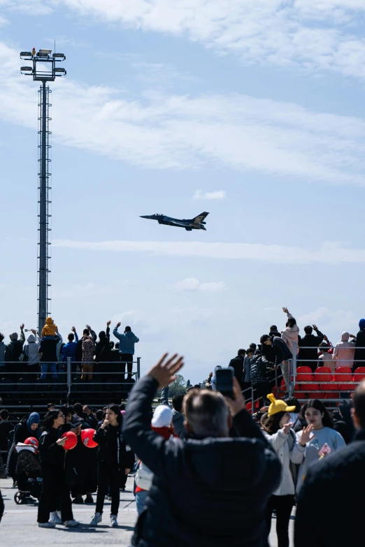 several people are watching a plane soar in the air