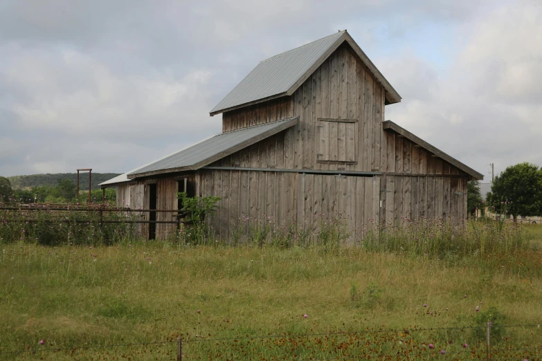 the wooden barn has a black roof and a metal roof