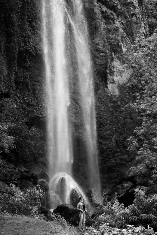 the dark waterfall in front of the men standing beneath it