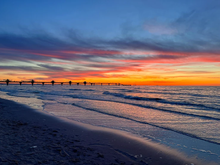 a view of an ocean and beach with some people walking on it