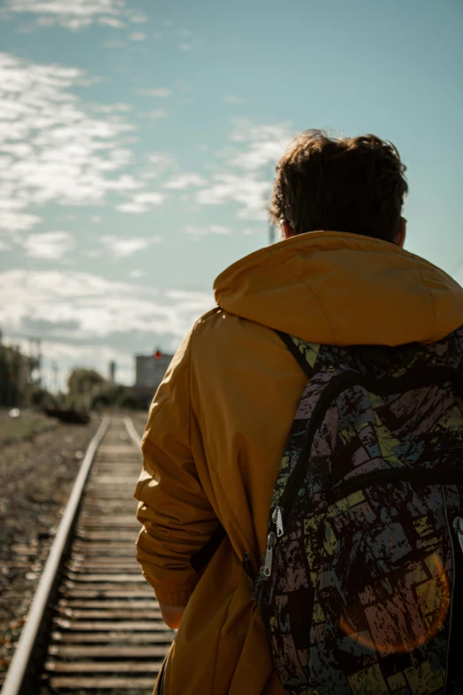 a man in yellow jacket and yellow parka standing by the train tracks