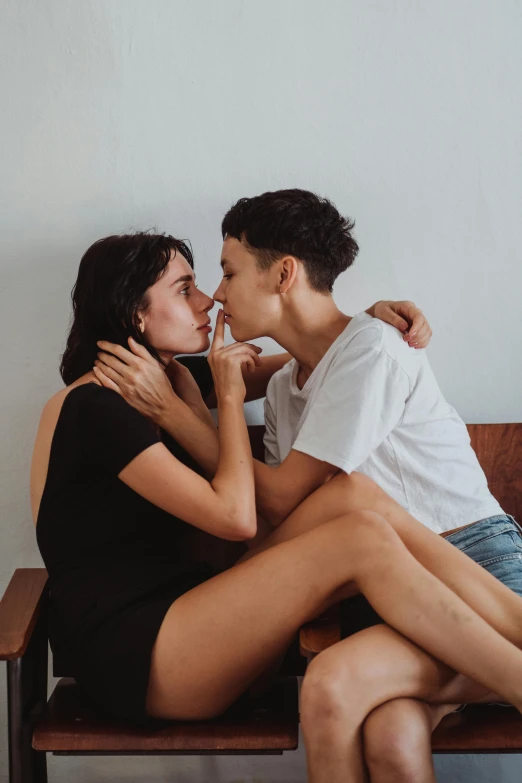 two people sitting on a bench and one kissing