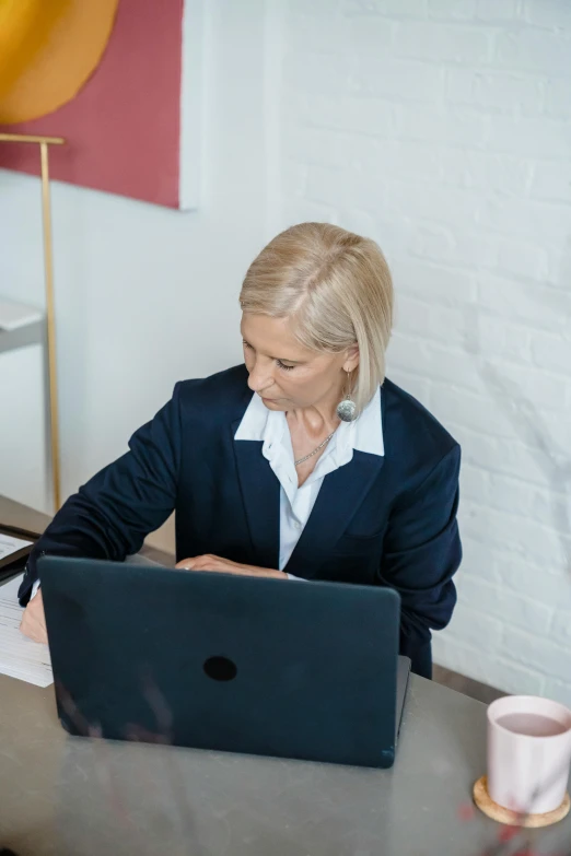 a woman sits at a desk working on a laptop