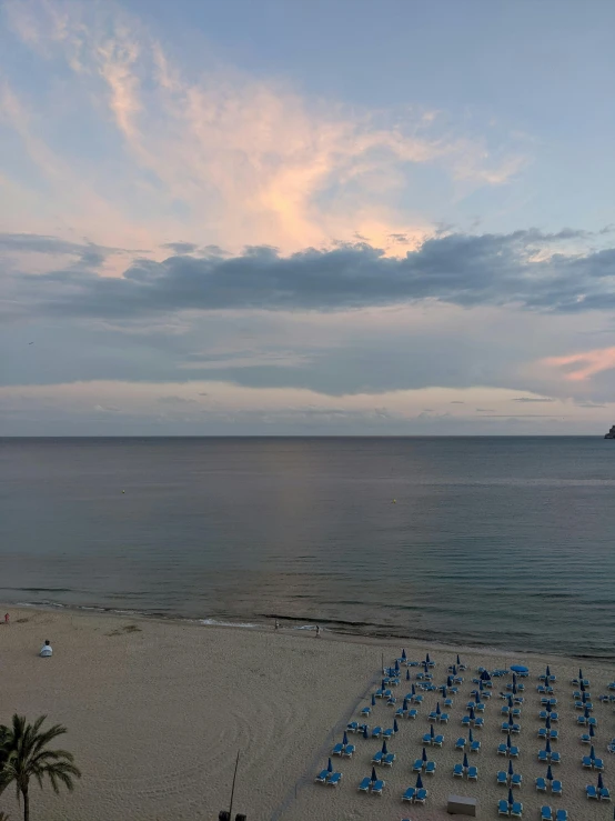 an empty beach is pictured at sunset with lounge chairs