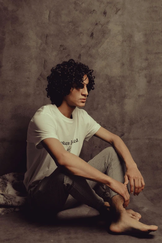 a man with a white shirt is sitting against a wall