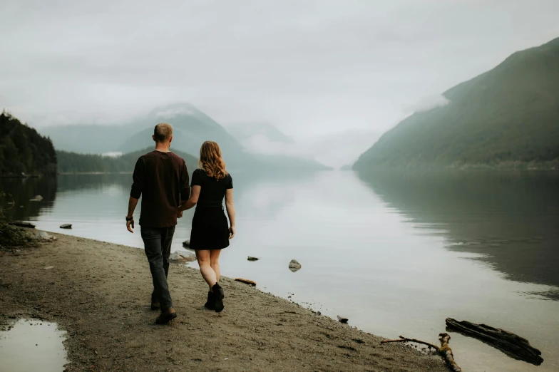 the couple are walking down the beach near the water