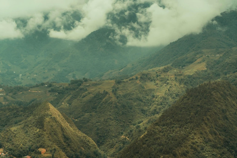 a valley surrounded by mountains that has clouds in the air