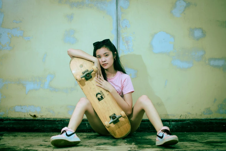 a girl is sitting down holding her skateboard