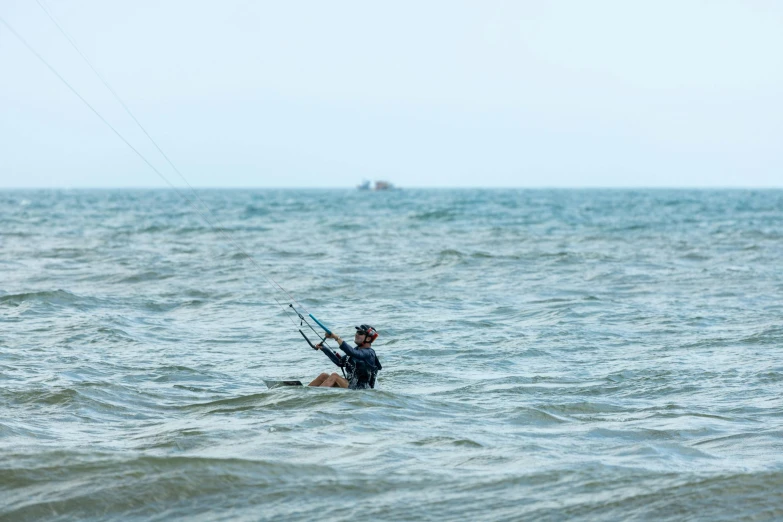 person in the ocean surfing on water with wind and sail