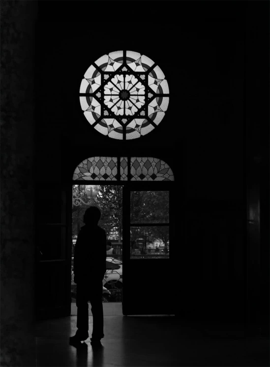 silhouette of person in dark building with large stain glass window