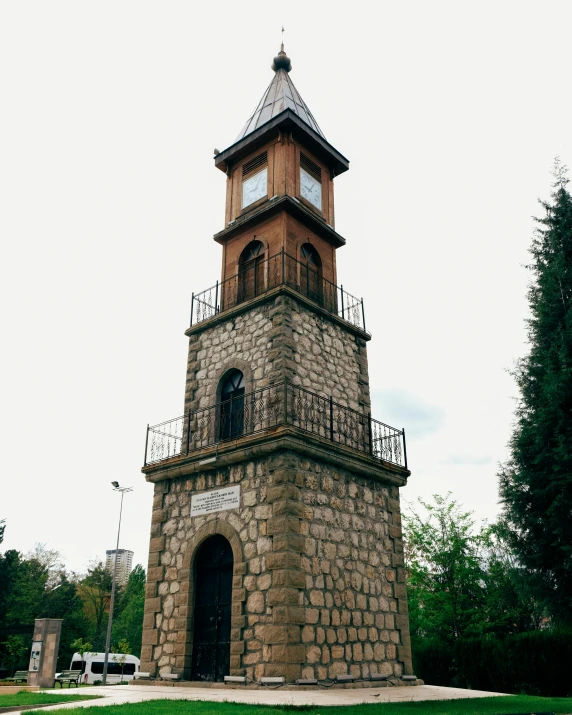 the clock tower stands tall and has an iron balcony