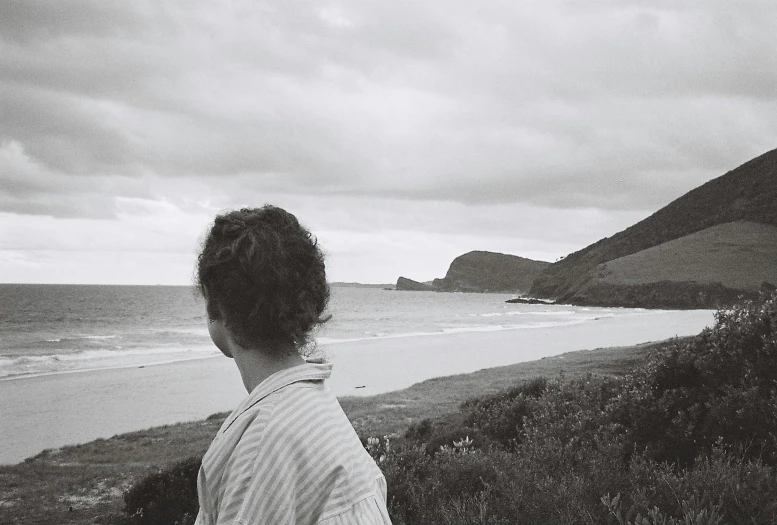 a black and white po of a person sitting at the beach