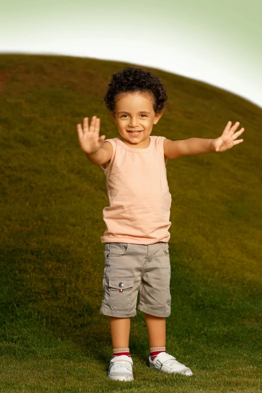 a little boy on a grassy hill making a hand sign