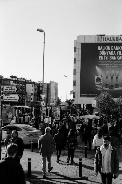 many people walking on a city street in front of stores