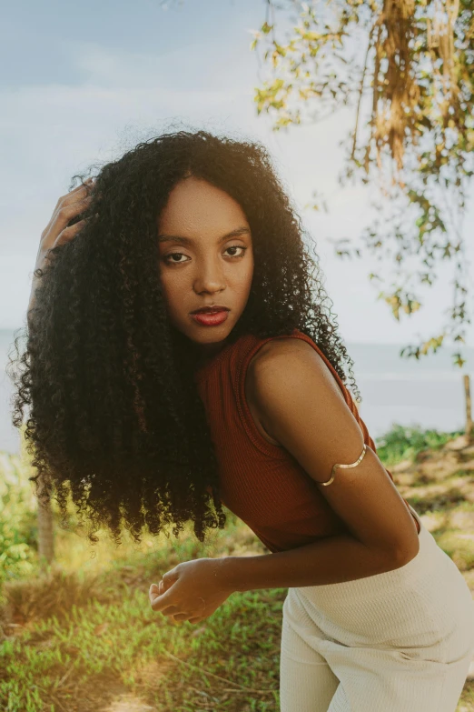 a young woman with curly hair standing in the sun