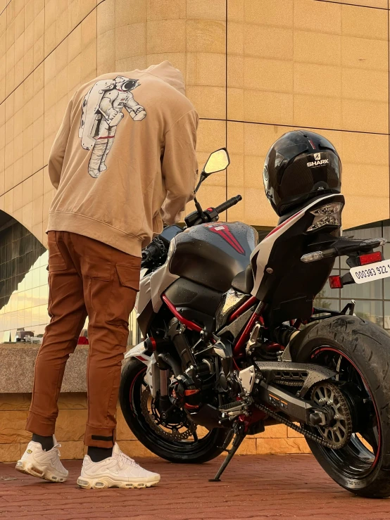 man standing next to his motorcycle in front of a building