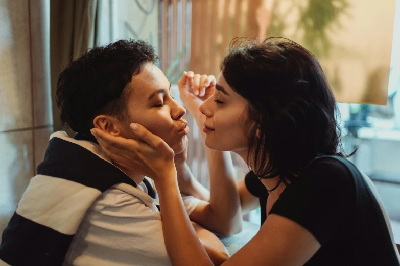 a couple sit next to each other with a girl touching his forehead