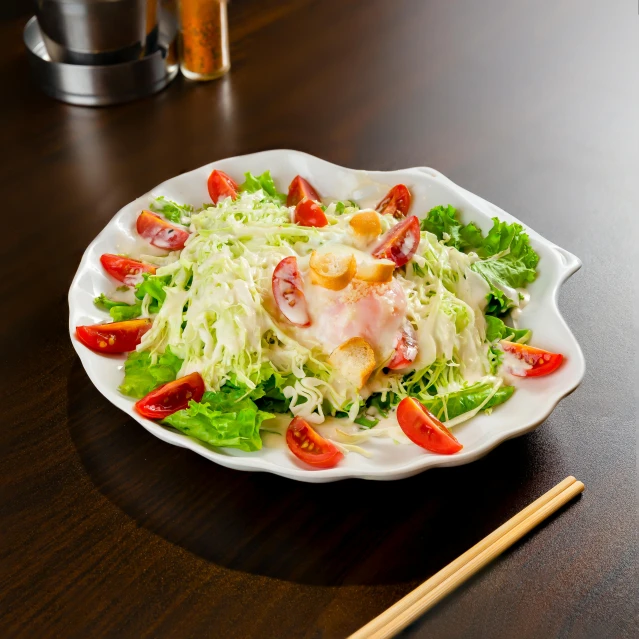 a plate full of salad with shrimp on it next to chopsticks