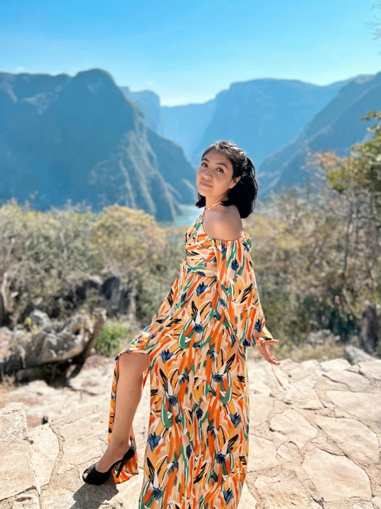 a woman sitting on a rock at the base of a mountain