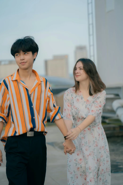 two people holding hands walking along a tarmac