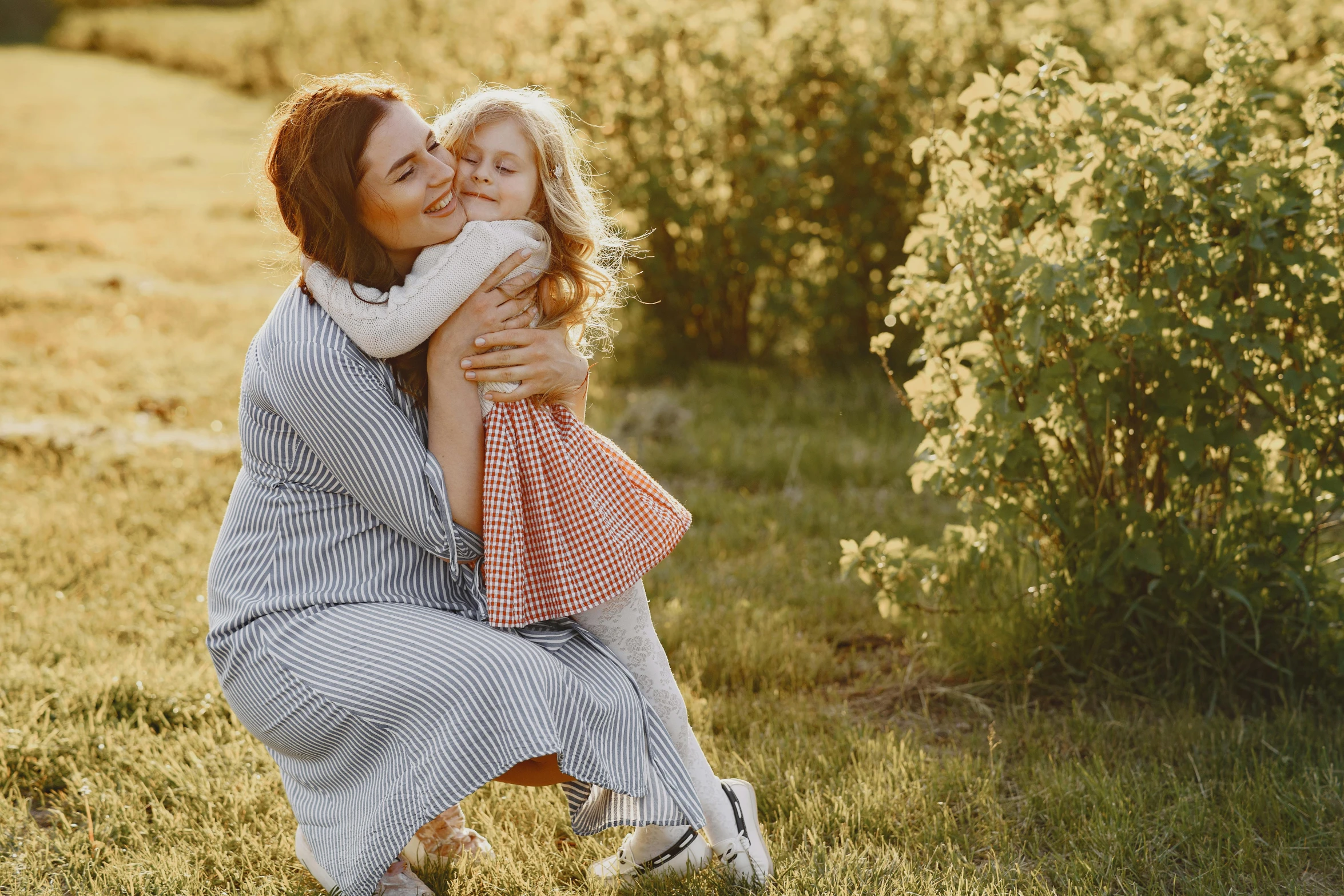 a woman hugs a  outside in a field