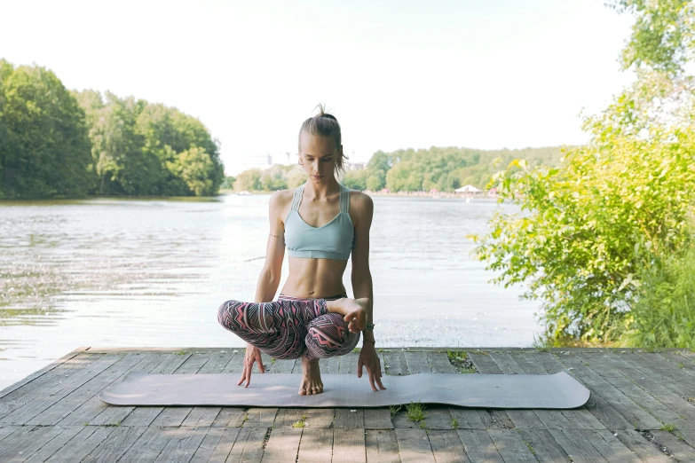 a woman doing yoga on a mat by the water