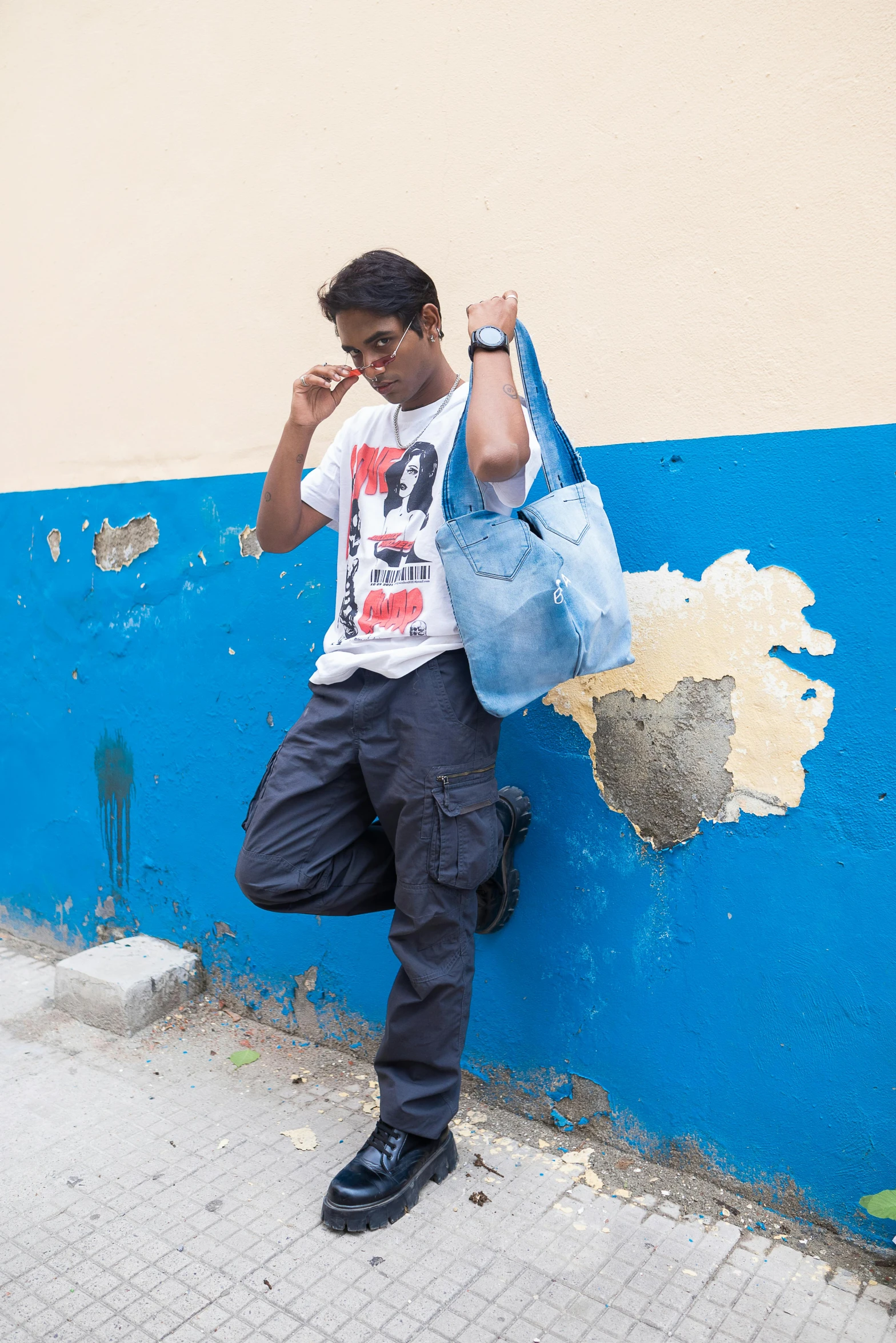 a man leaning on a blue wall holding a phone