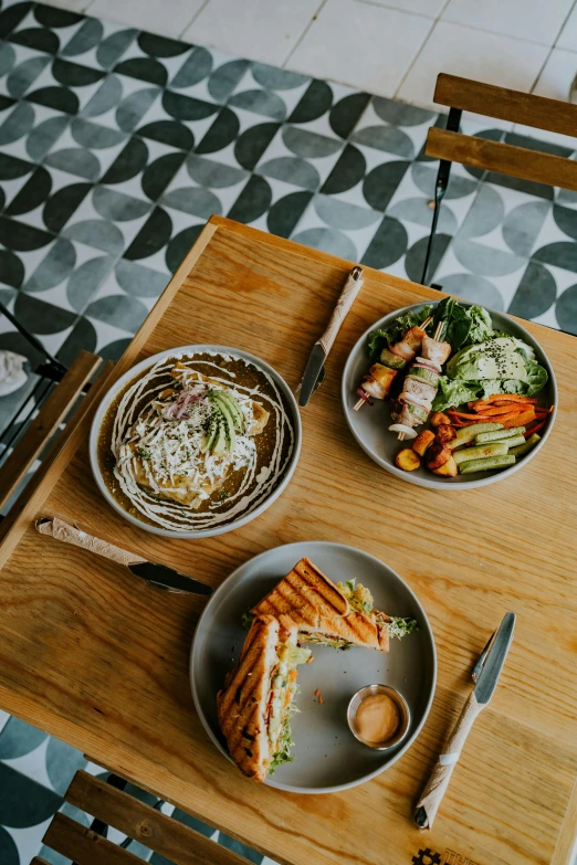 plated food next to bowl of salad and fork on wooden serving board