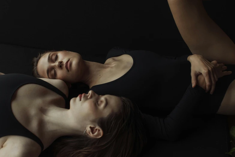 two women lie down on the bed next to each other