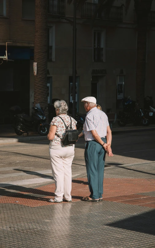 two older people standing on a cobblestone sidewalk