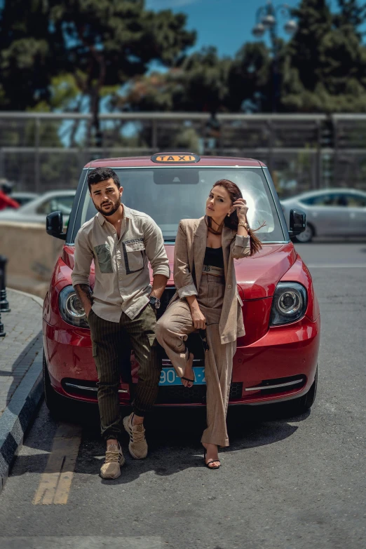 a man and woman sitting on the bumper of a red car