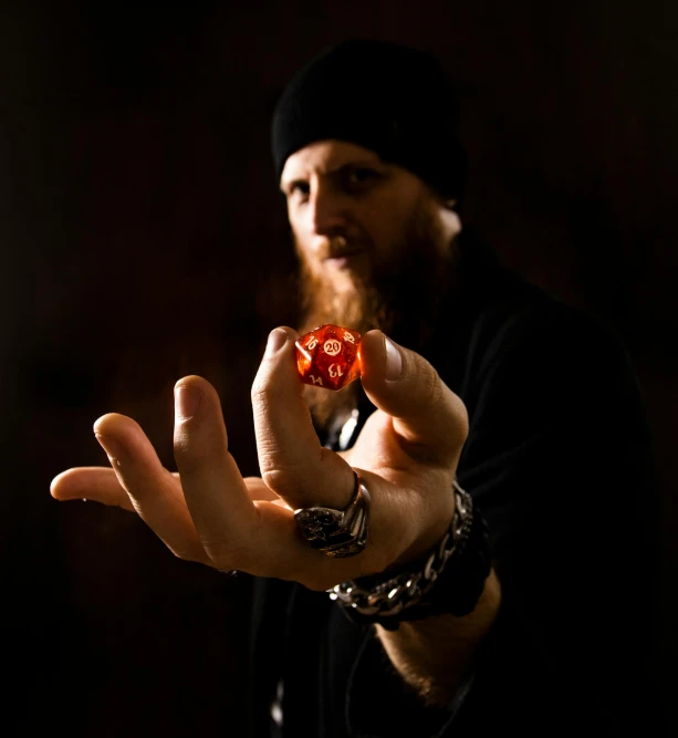 a man with long hair holding a red dice