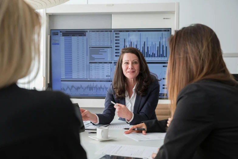 a woman sitting at a table in front of a computer screen