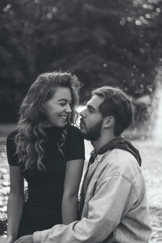 a couple sitting next to each other in front of a fountain