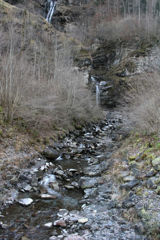 a stream running between two dry grassy hills