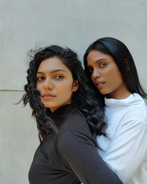 two girls are standing near each other with long hair