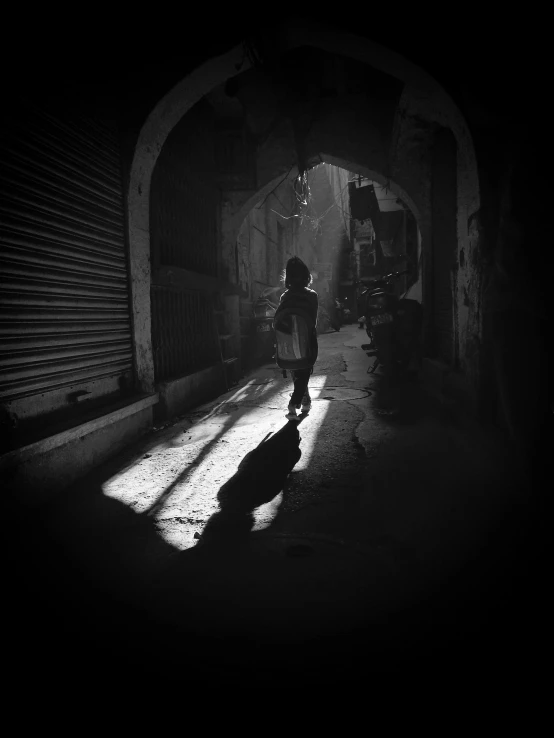 the silhouette of a woman walking in an alley